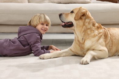 Photo of Cute little child with Golden Retriever on floor at home. Adorable pet