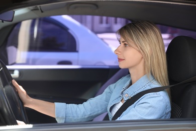 Woman with fastened safety belt on driver's seat in car