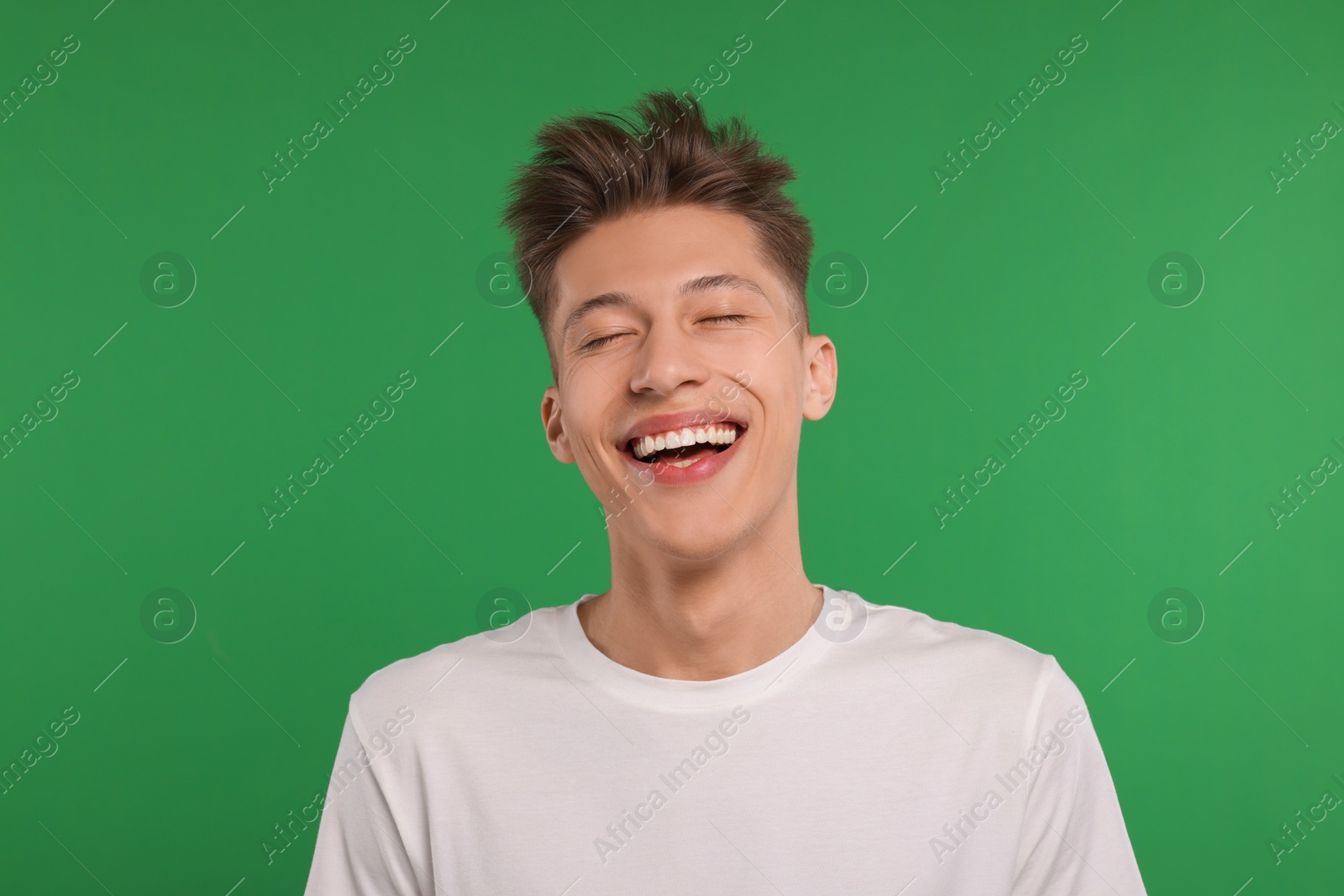 Photo of Portrait of young man laughing on green background