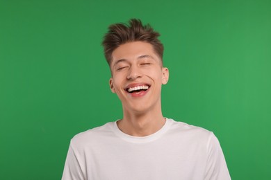 Portrait of young man laughing on green background