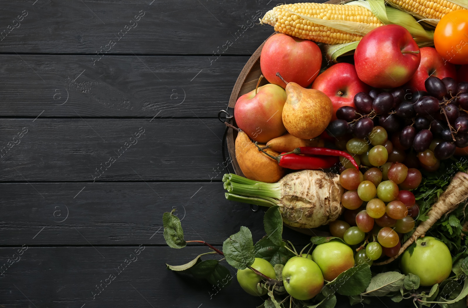 Photo of Different fresh vegetables and fruits on black wooden table, top view with space for text. Farmer harvesting