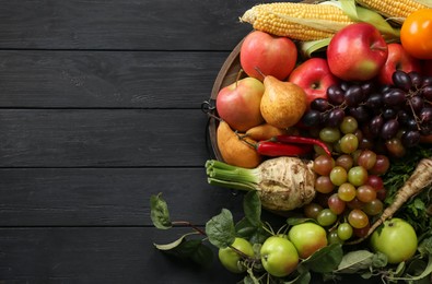 Photo of Different fresh vegetables and fruits on black wooden table, top view with space for text. Farmer harvesting