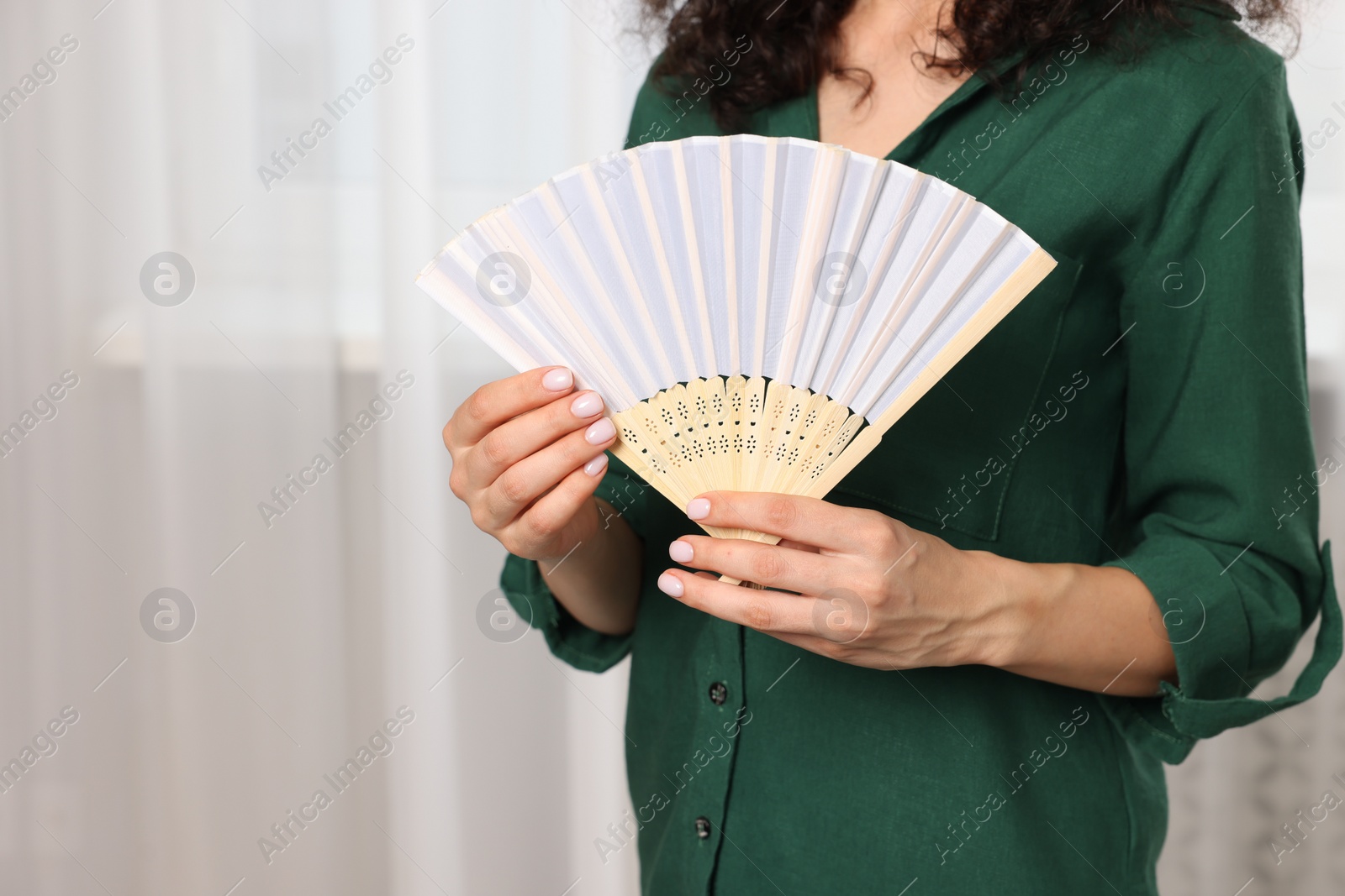 Photo of Woman with hand fan indoors, closeup view