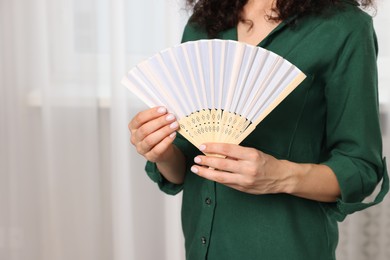 Woman with hand fan indoors, closeup view