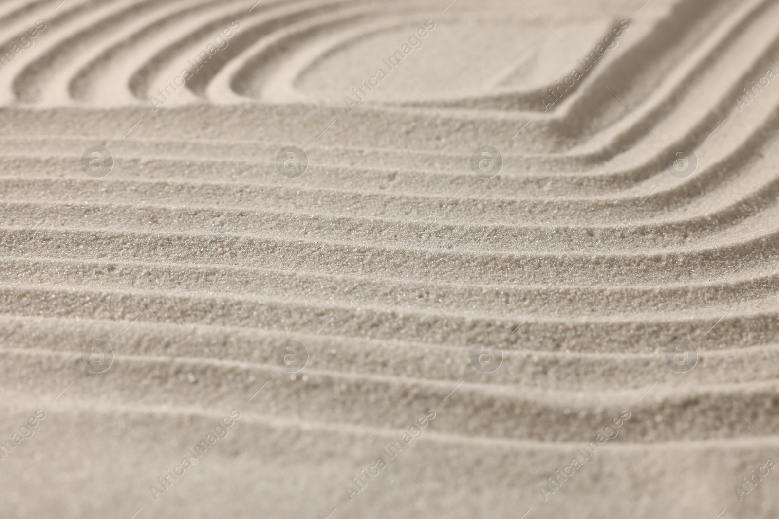 Photo of Beautiful lines drawn on sand, closeup. Zen garden