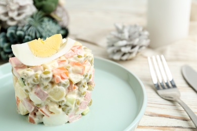 Photo of Traditional russian salad Olivier served on white wooden table, closeup