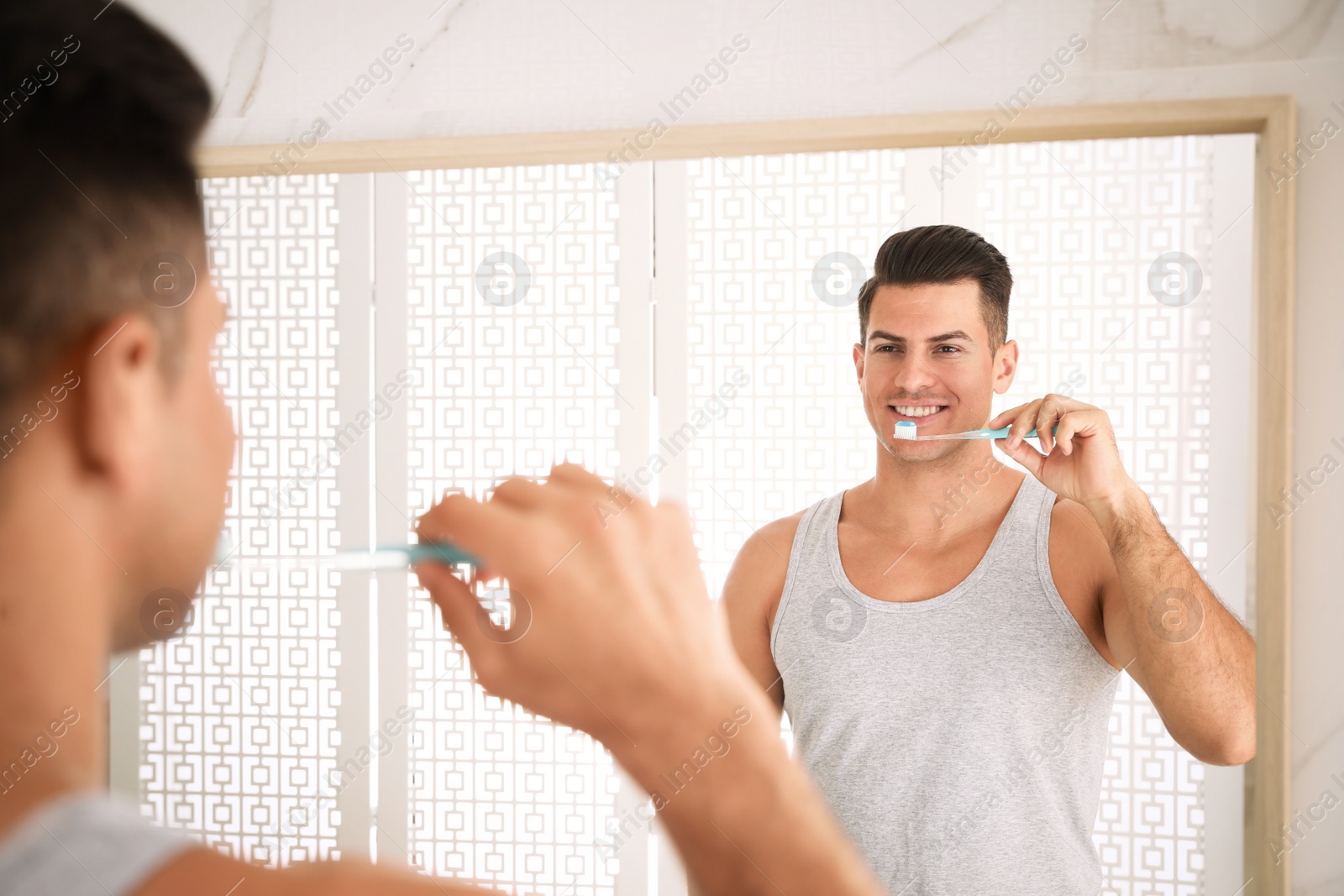 Photo of Man brushing teeth in front of mirror at home