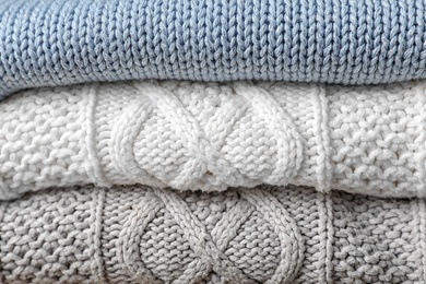 Photo of Stack of folded warm knitted sweaters, closeup