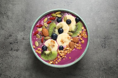 Delicious acai smoothie with granola and fruits on grey table, top view