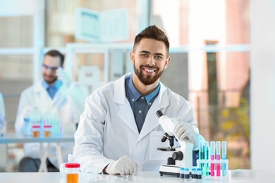 Photo of Young scientist with microscope in laboratory. Chemical analysis