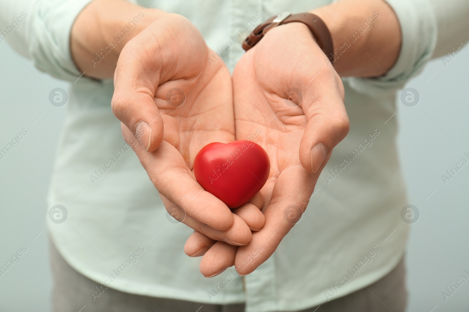 Photo of Man holding small red heart, closeup. Heart attack concept