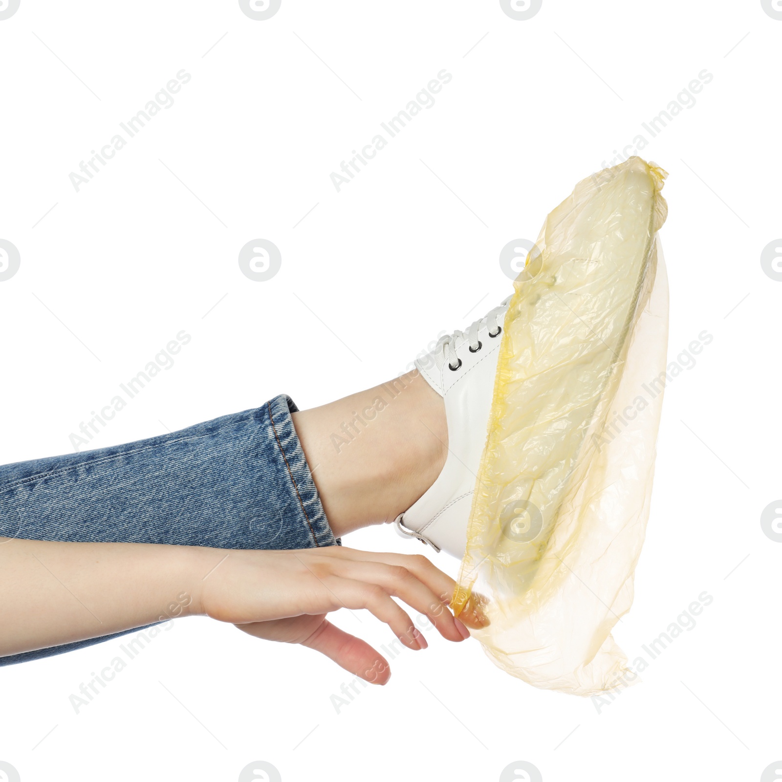 Photo of Woman wearing yellow shoe cover onto her sneaker against white background, closeup