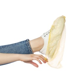 Photo of Woman wearing yellow shoe cover onto her sneaker against white background, closeup