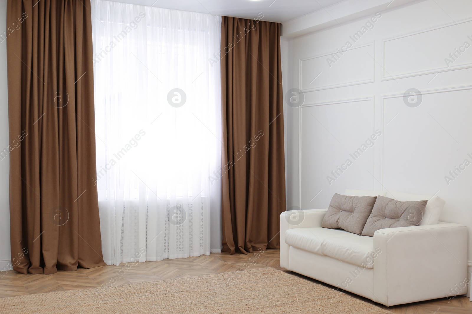 Photo of Sofa and window with brown curtains in simple room interior