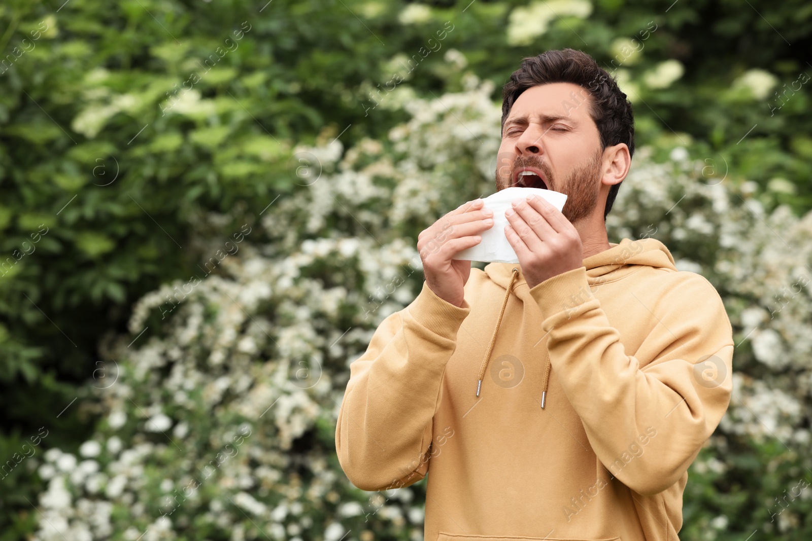 Photo of Man suffering from seasonal spring allergy outdoors, space for text