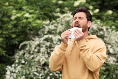 Photo of Man suffering from seasonal spring allergy outdoors, space for text