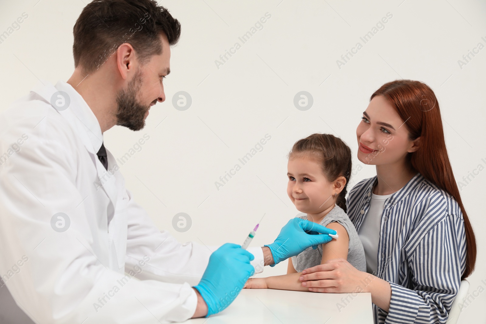 Photo of Children's hepatitis vaccination. Mother with her daughter in clinic. Doctor giving injection to little girl