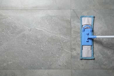 Photo of Cleaning grey marble floor with mop indoors, top view. Space for text