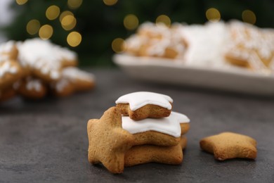 Photo of Decorated cookies on grey table against blurred Christmas lights, closeup