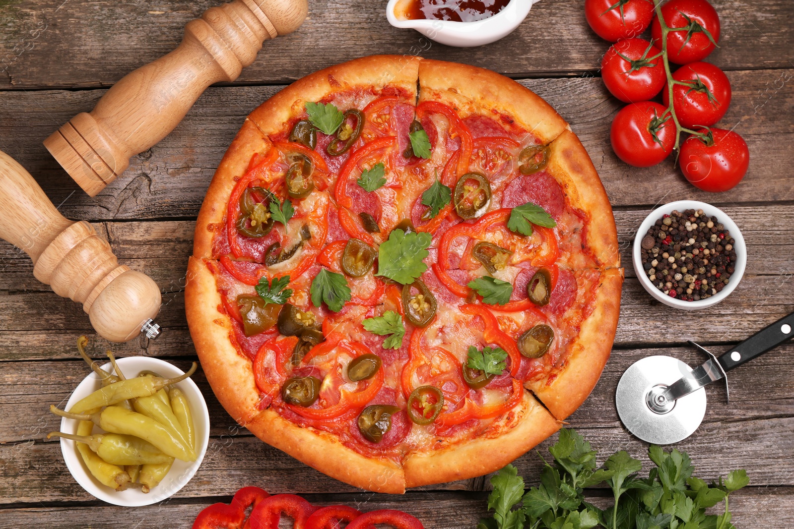 Photo of Delicious pizza Diablo, ingredients and cutter on wooden table, flat lay