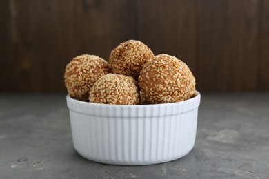 Photo of Bowl of delicious sesame balls on grey table, closeup