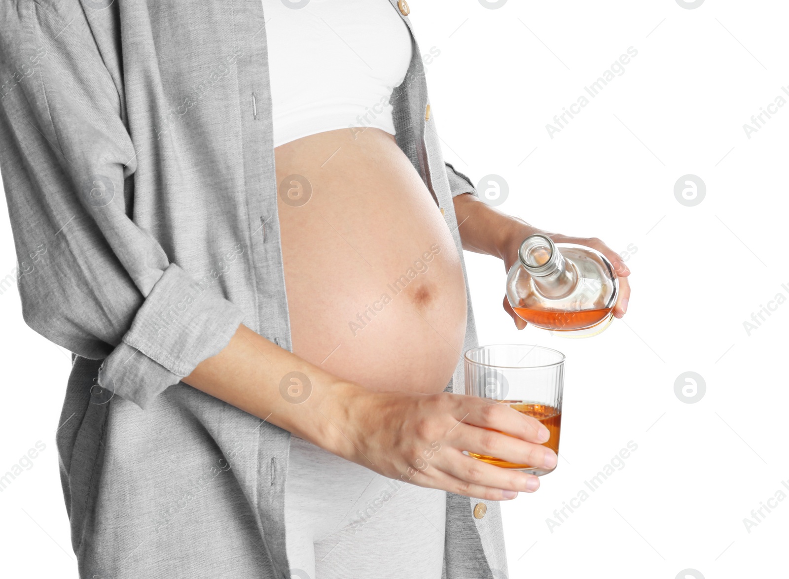 Photo of Pregnant woman pouring whiskey into glass on white background. Alcohol addiction