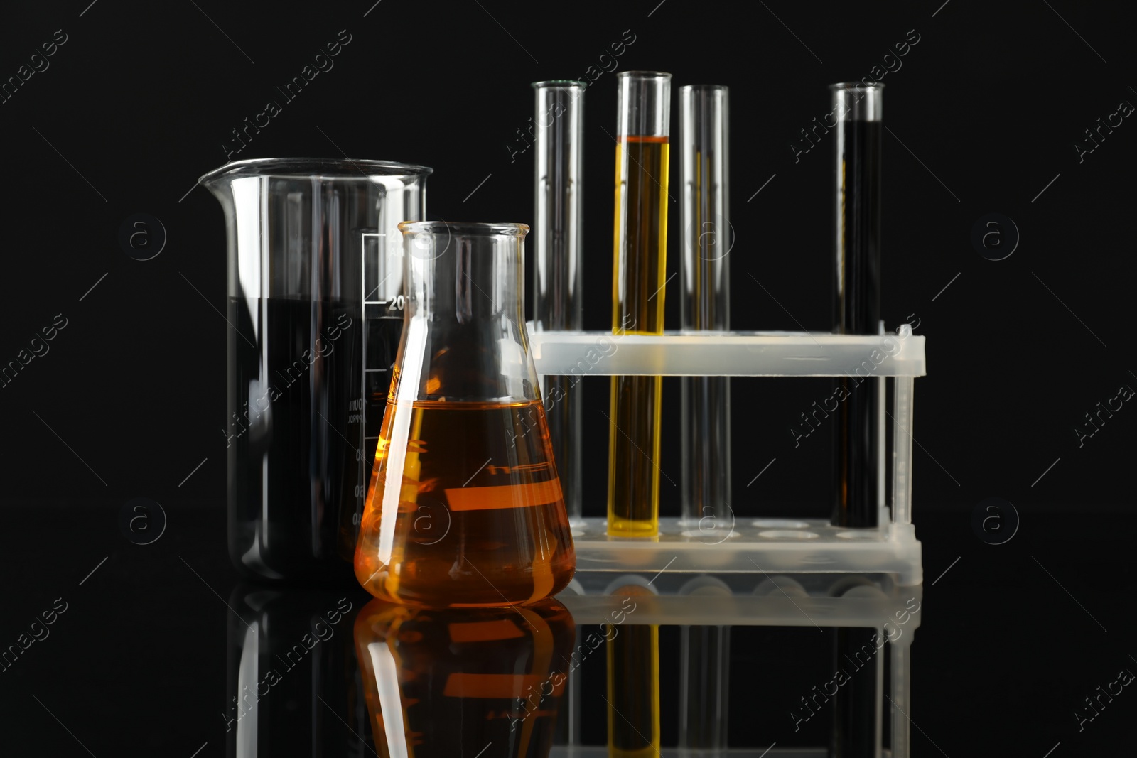 Photo of Laboratory glassware with different types of oil on black background