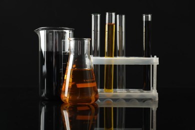 Laboratory glassware with different types of oil on black background