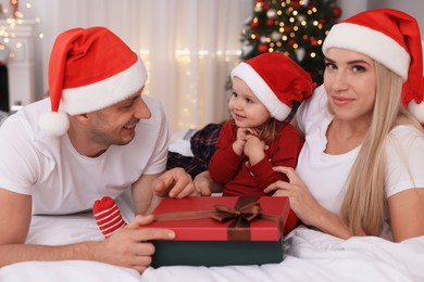 Photo of Happy family with Santa hats in room decorated for Christmas