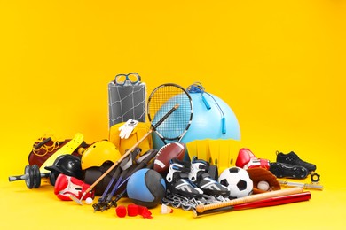 Photo of Many different sports equipment on yellow background