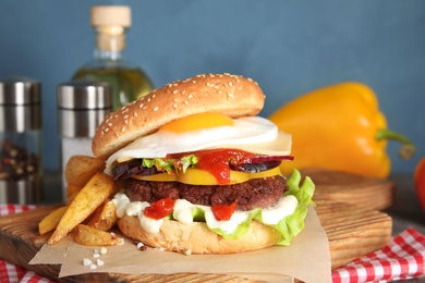 Photo of Tasty burger with fried egg on wooden board