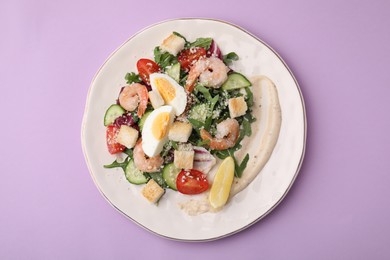 Photo of Delicious Caesar salad with shrimps on violet background, top view