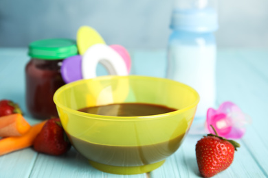 Healthy baby food and ingredients on light blue wooden table