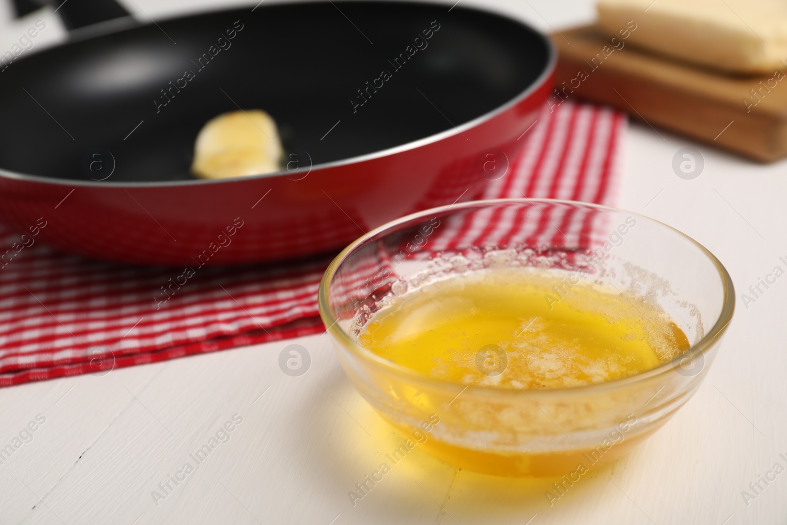 Photo of Melted butter in glass bowl on white wooden table, closeup