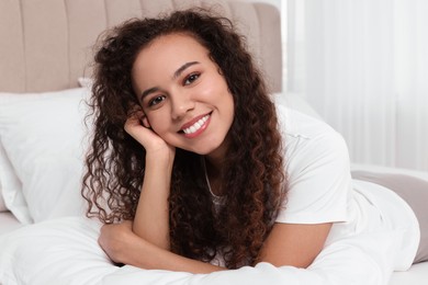 Happy African American woman lying on bed at home