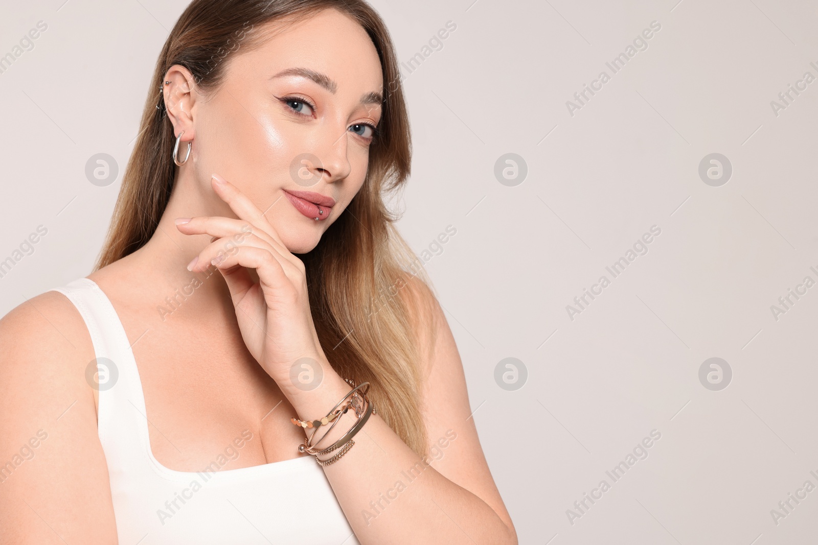 Photo of Young woman with lip and ear piercings on white background, space for text