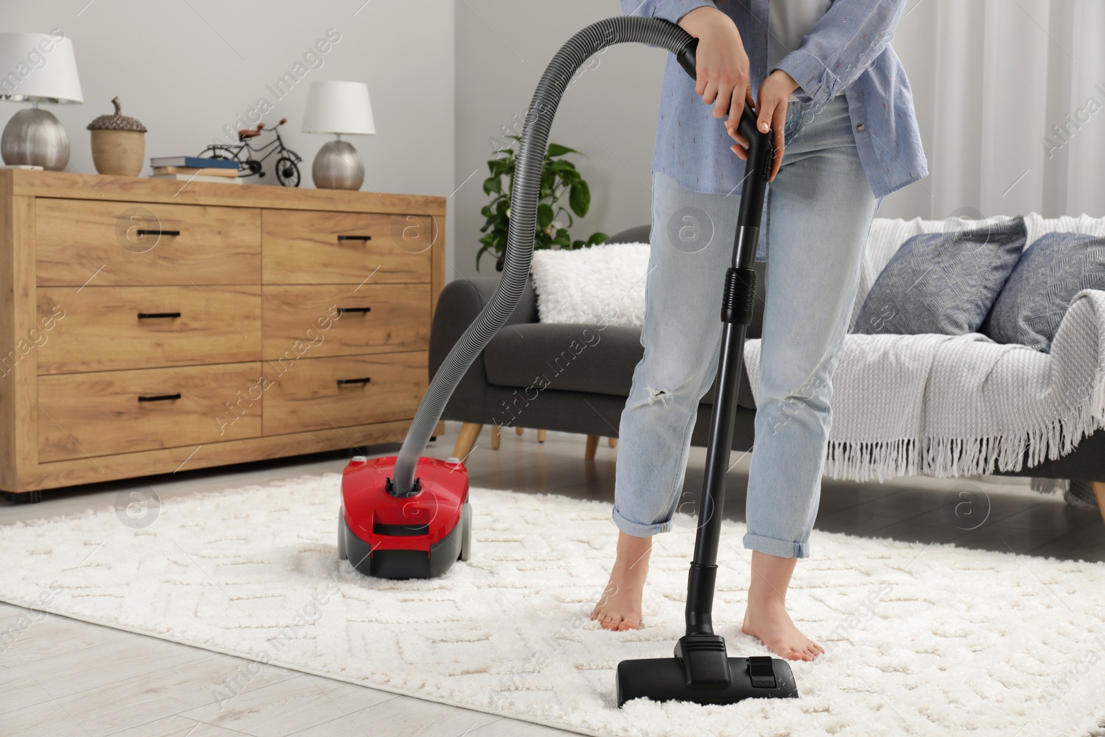 Photo of Woman cleaning carpet with vacuum cleaner at home, closeup