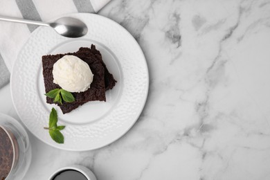 Photo of Tasty brownies with ice cream and mint served on white marble table, flat lay. Space for text