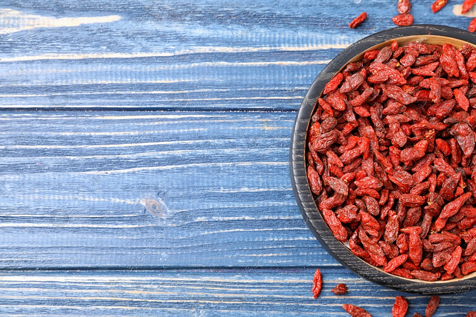 Photo of Dried goji berries on blue wooden table, top view. Space for text