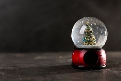 Photo of Snow globe with Christmas tree on grey table, space for text