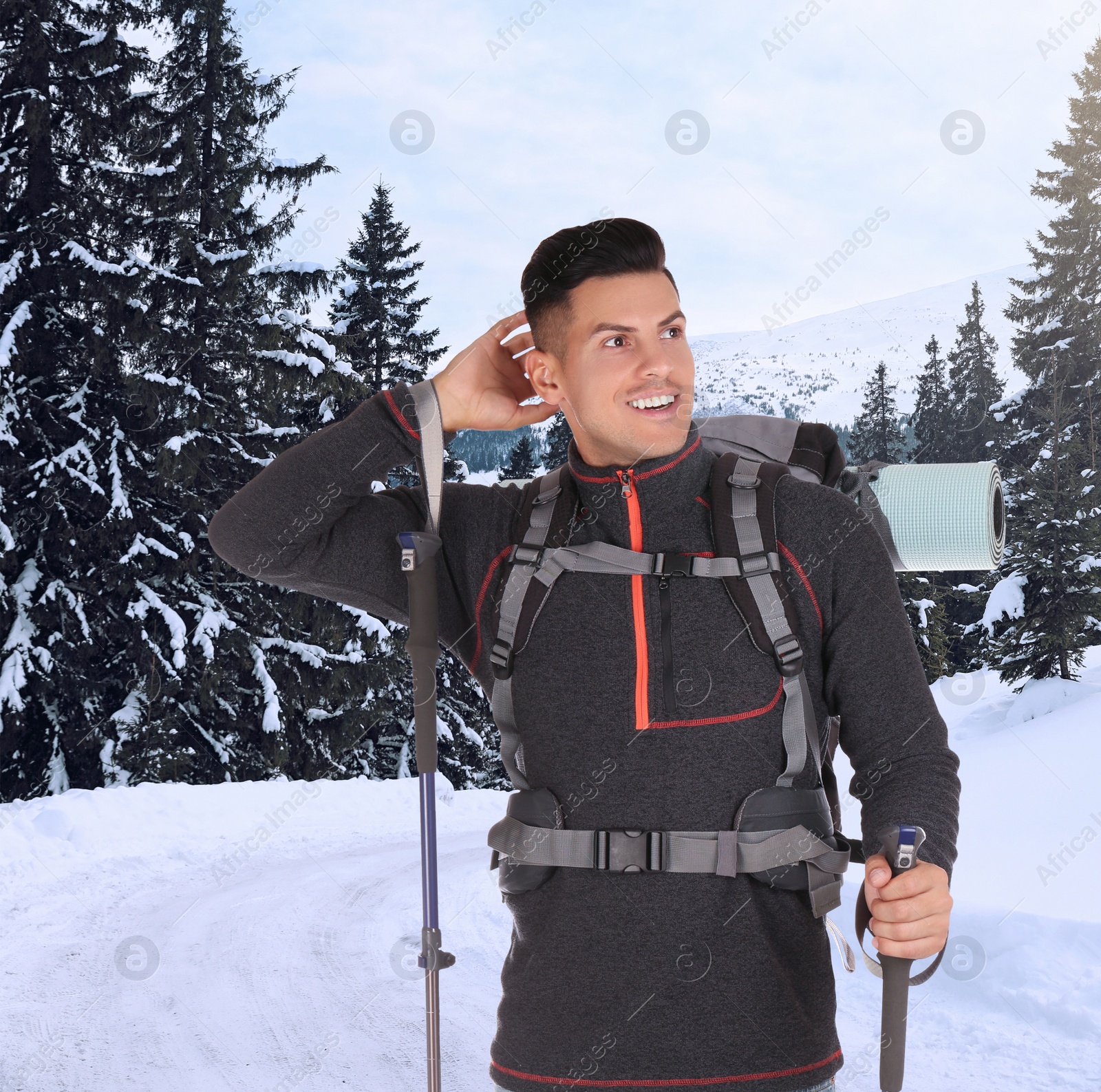 Image of Man with backpack and trekking poles in snowy mountains