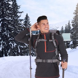 Image of Man with backpack and trekking poles in snowy mountains