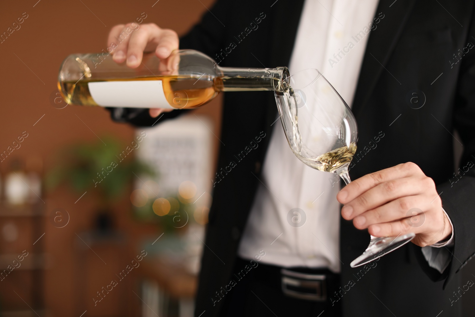 Photo of Man pouring delicious wine into glass indoors