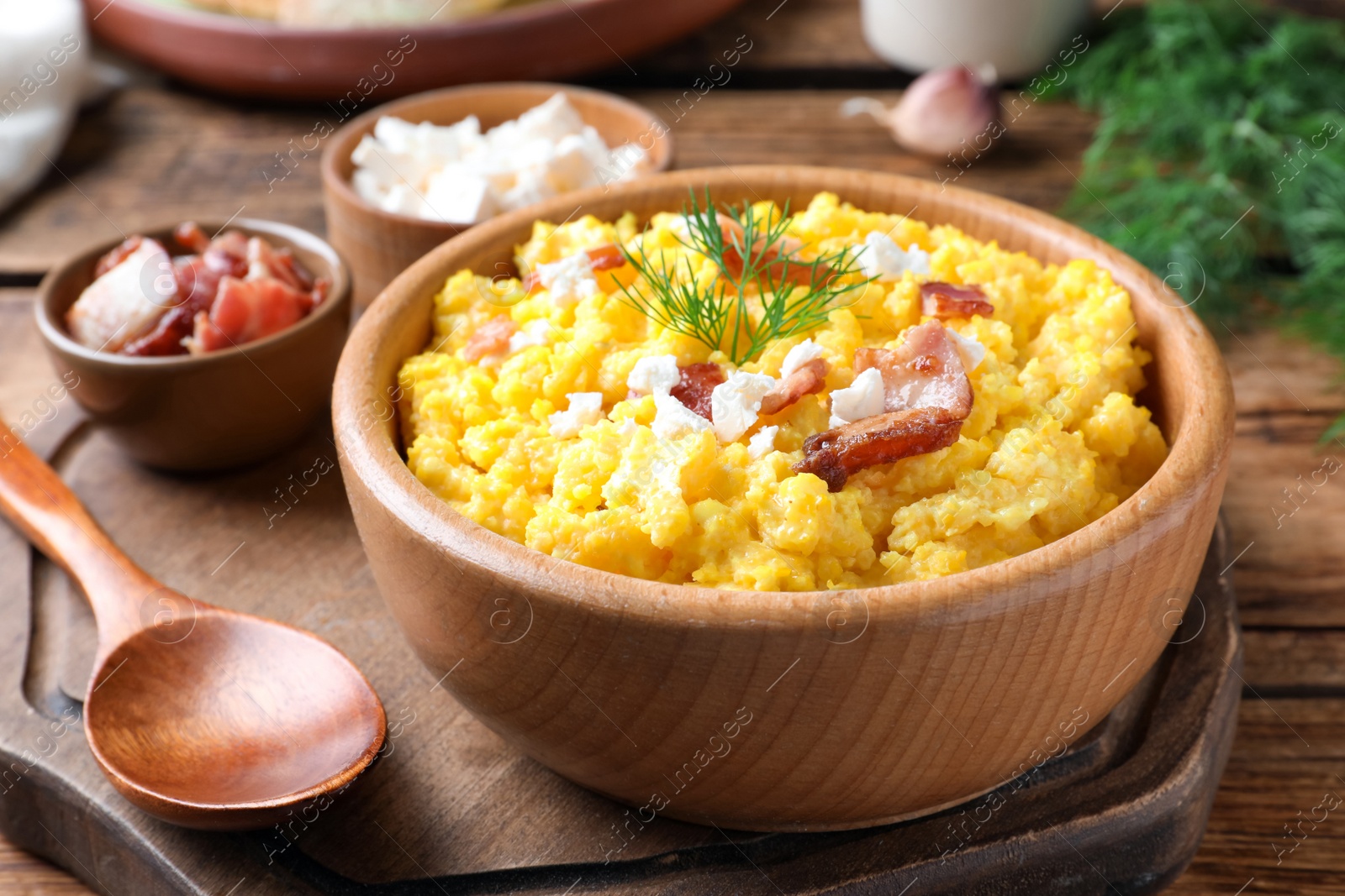 Photo of Tasty banosh served with brynza and pork cracklings on wooden table, closeup. Traditional Ukrainian dish