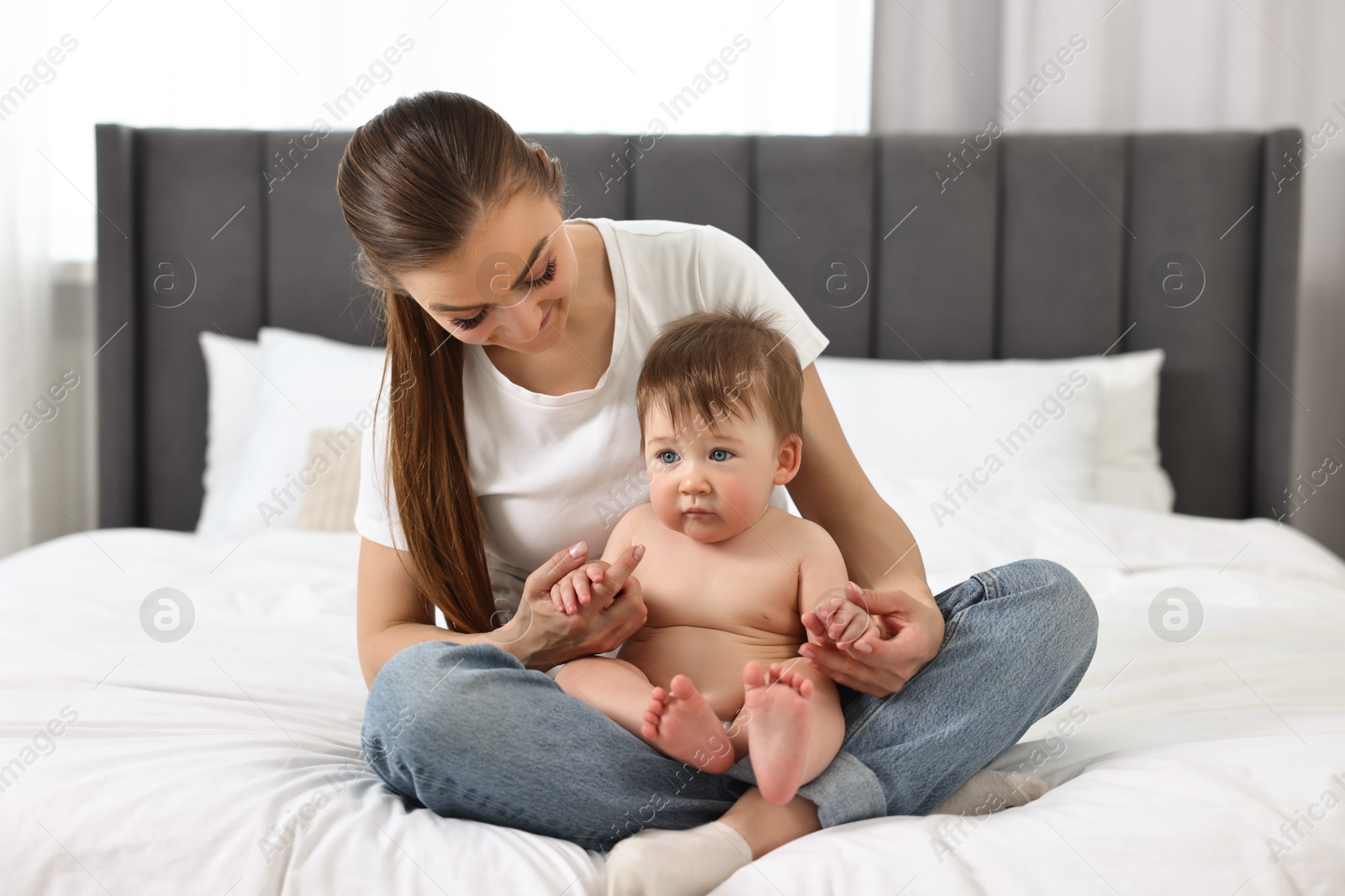 Photo of Mother sitting with her baby on bed at home