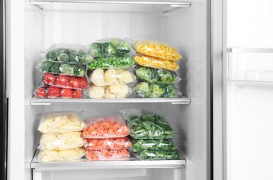 Plastic bags with different frozen vegetables in refrigerator