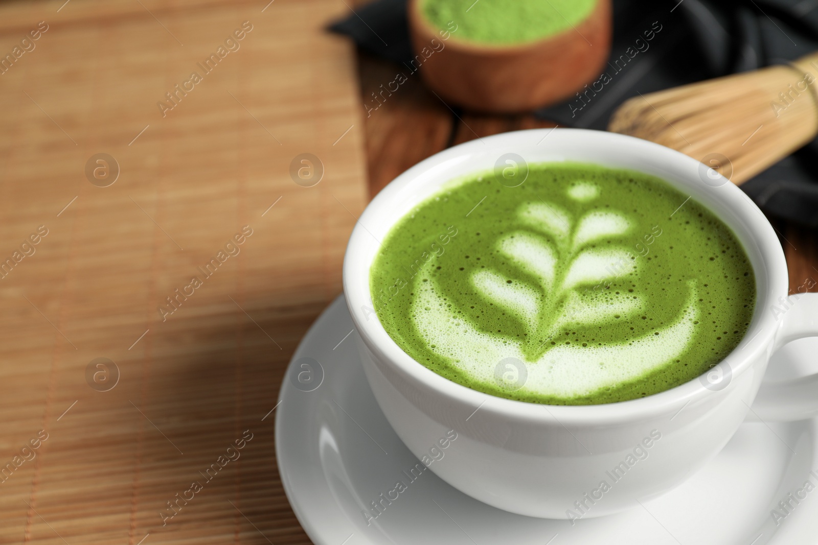 Photo of Delicious matcha latte in cup on table, closeup. Space for text