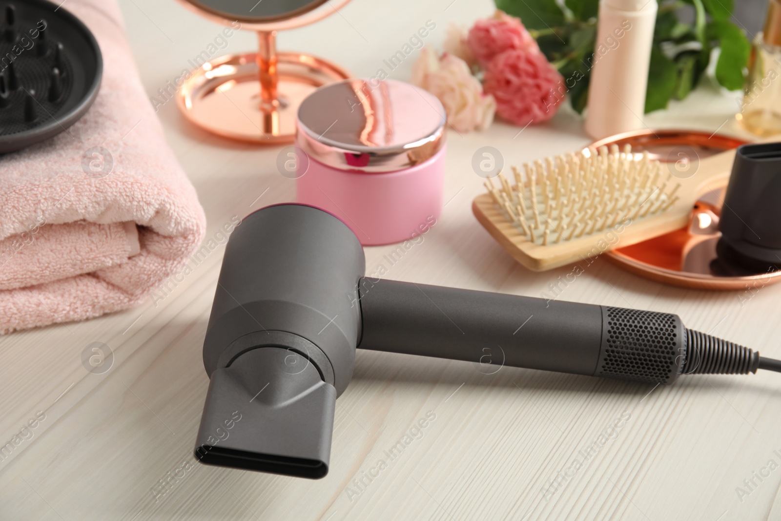 Photo of Hair care product and dryer on white wooden table