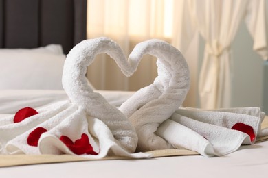 Photo of Honeymoon. Swans made of towels and rose petals on bed in room
