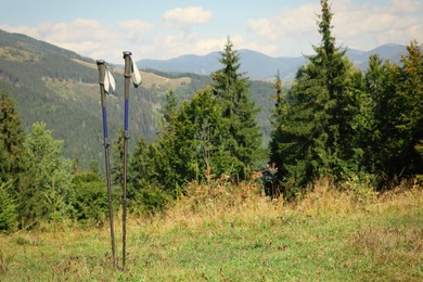 Photo of Trekking poles in mountains, space for text. Hiking accessory